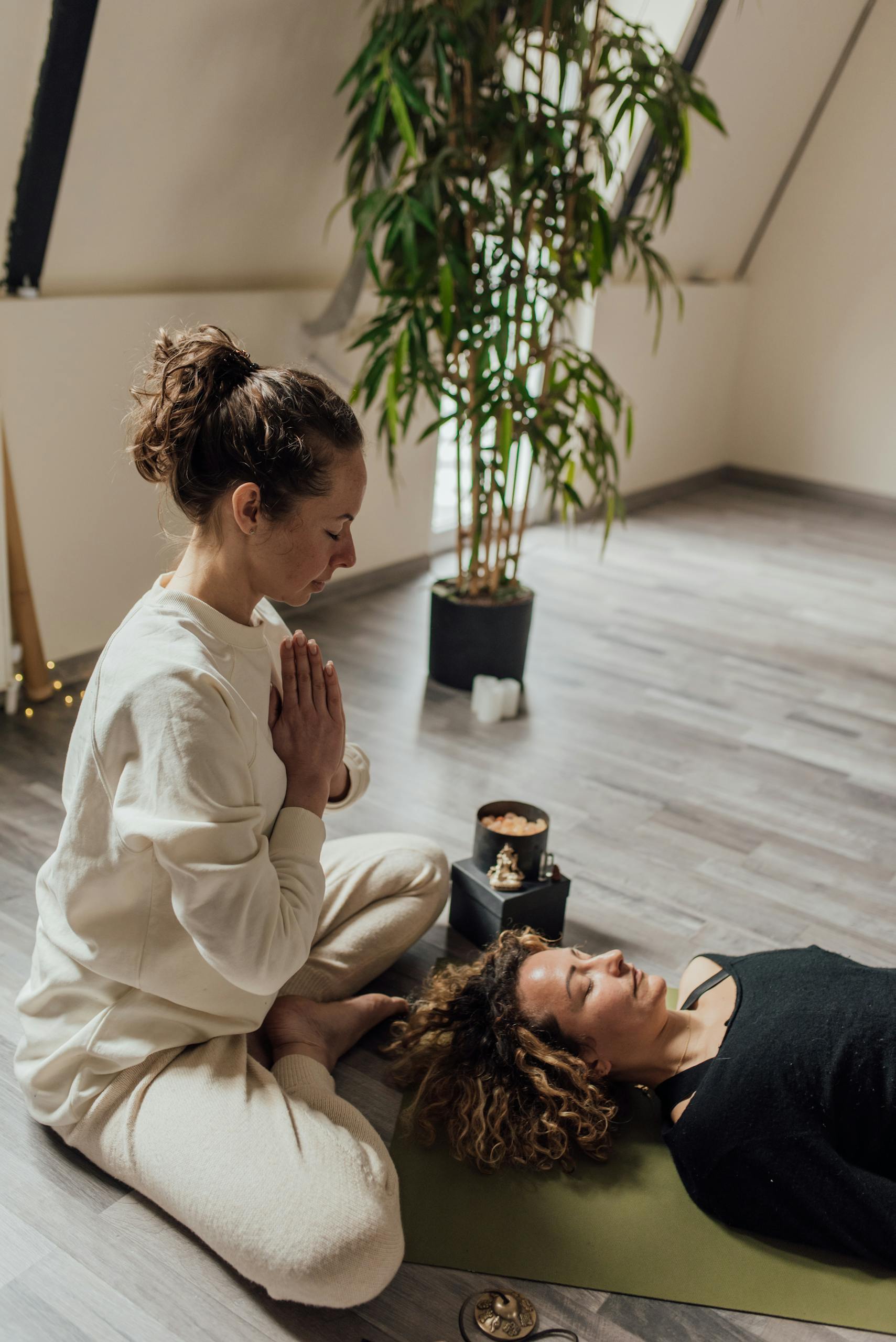 A Woman in Yoga Position Beside a Woman Lying on Floor