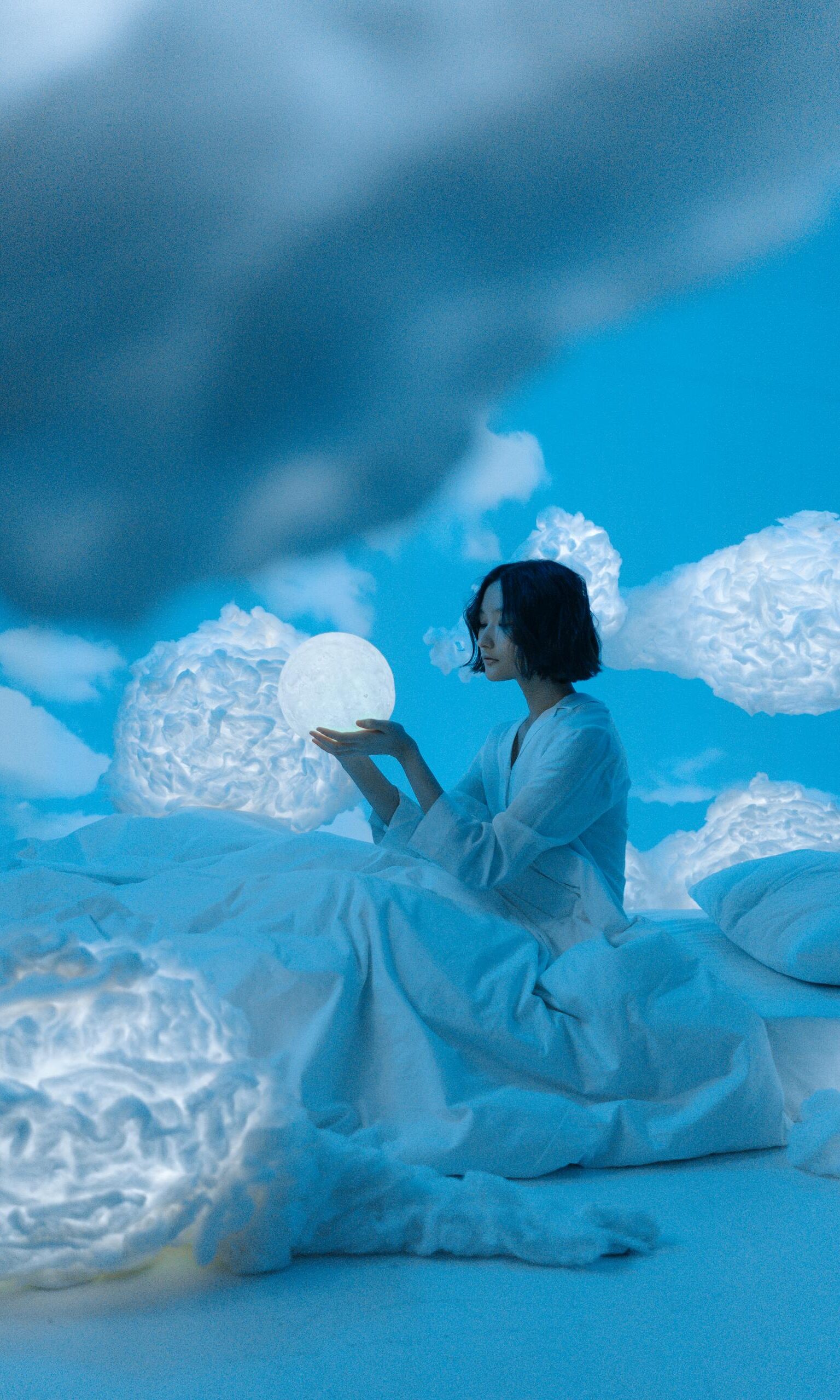 Woman Sitting on White Bed Among Clouds