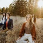 A serene outdoor meditation session with a group of women in an autumn park setting.